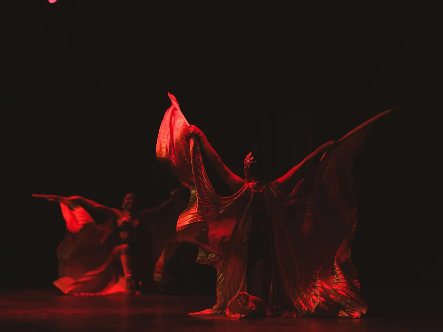 Dramatische Tanzperformance auf einer dunklen Bühne in rotem Licht